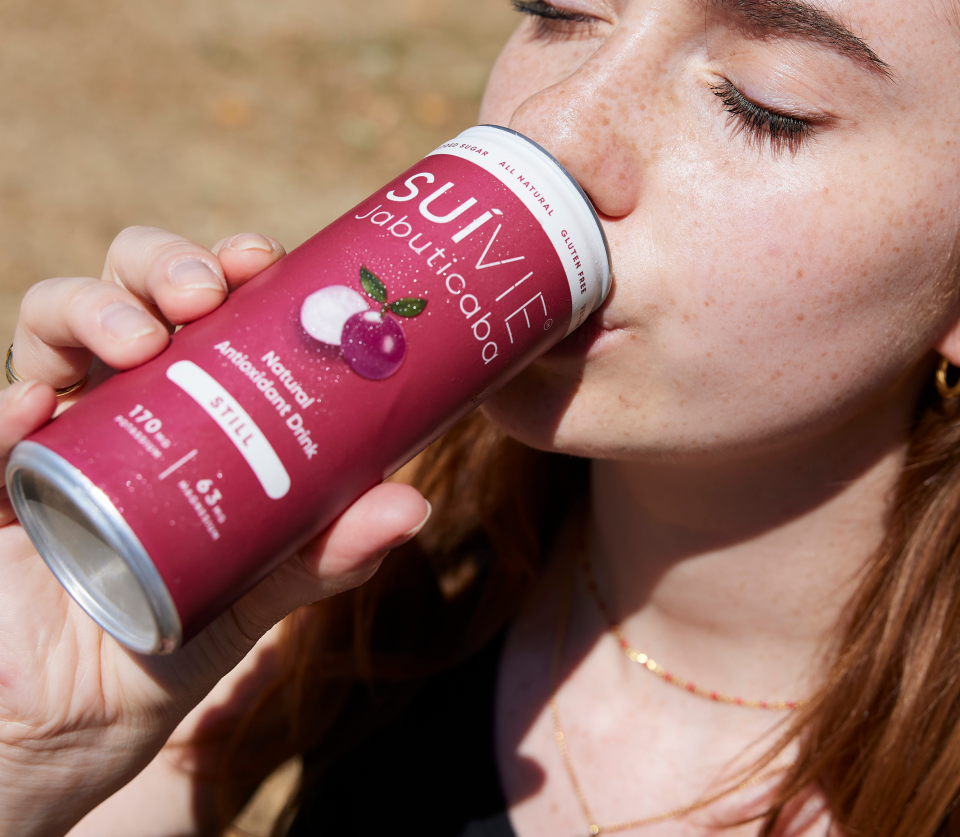 Woman enjoying a fresh Suivie Jabuticaba still Brazilian natural antioxidant drink